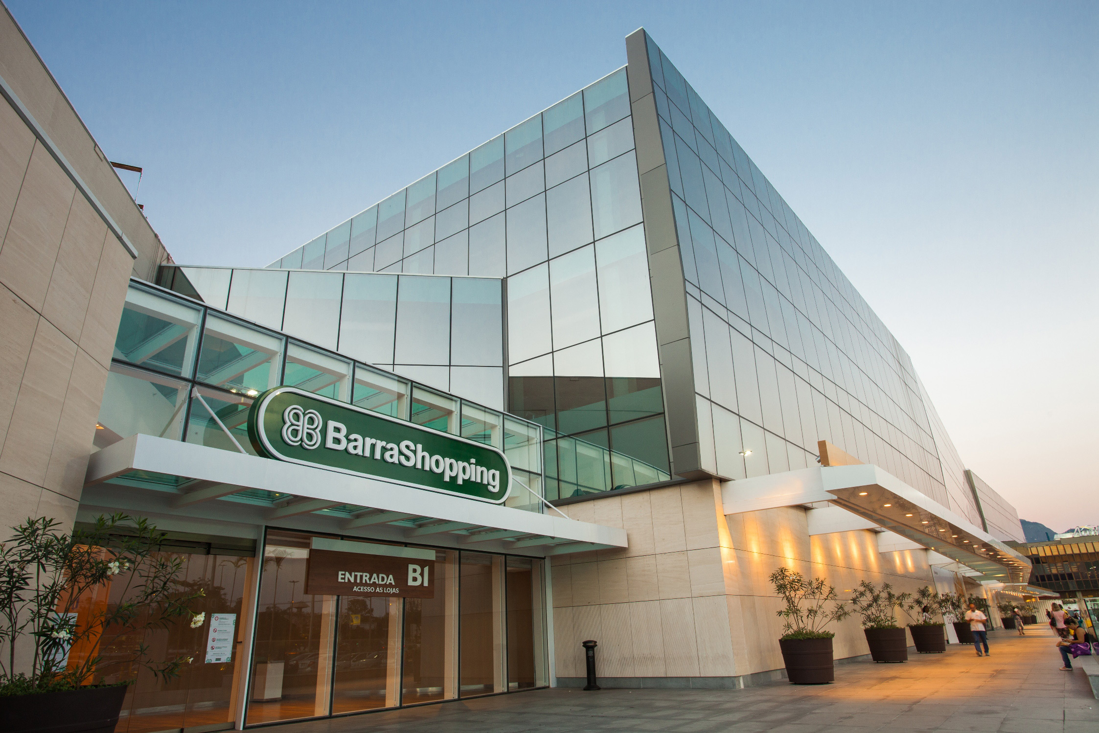 A entrada de um shopping center moderno com fachada de vidro e o letreiro "BarraShopping".