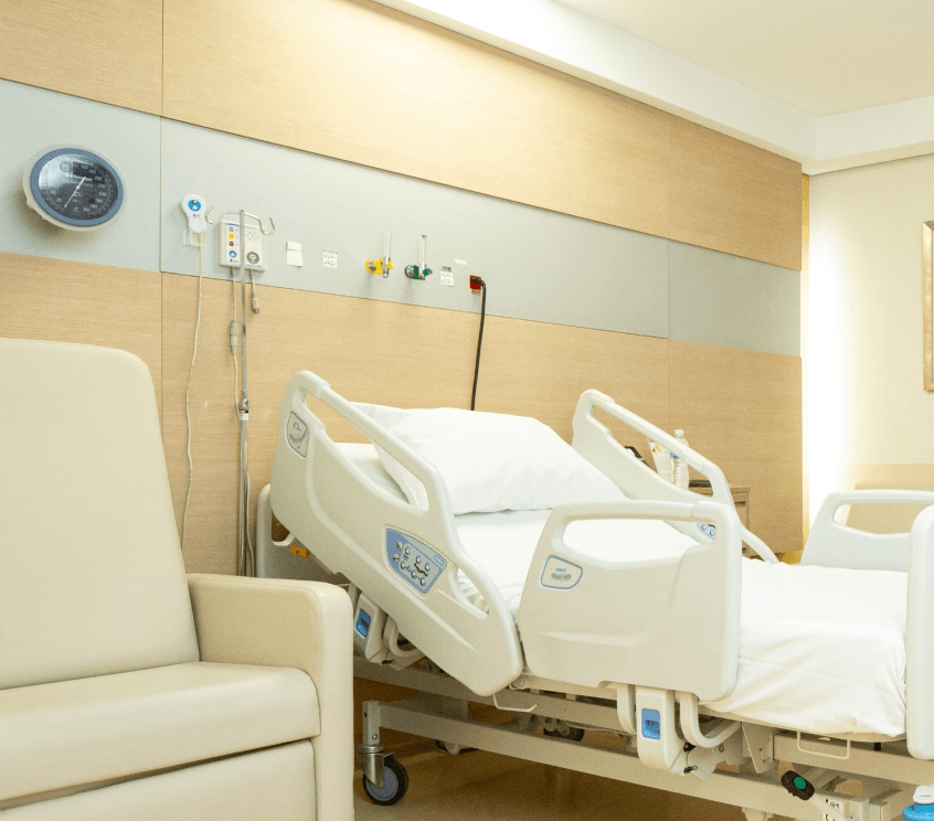 Quarto do Hospital Santa Paula, em São Paulo, no Brooklin, moderno com cama ajustável, poltrona e equipamentos médicos na parede.