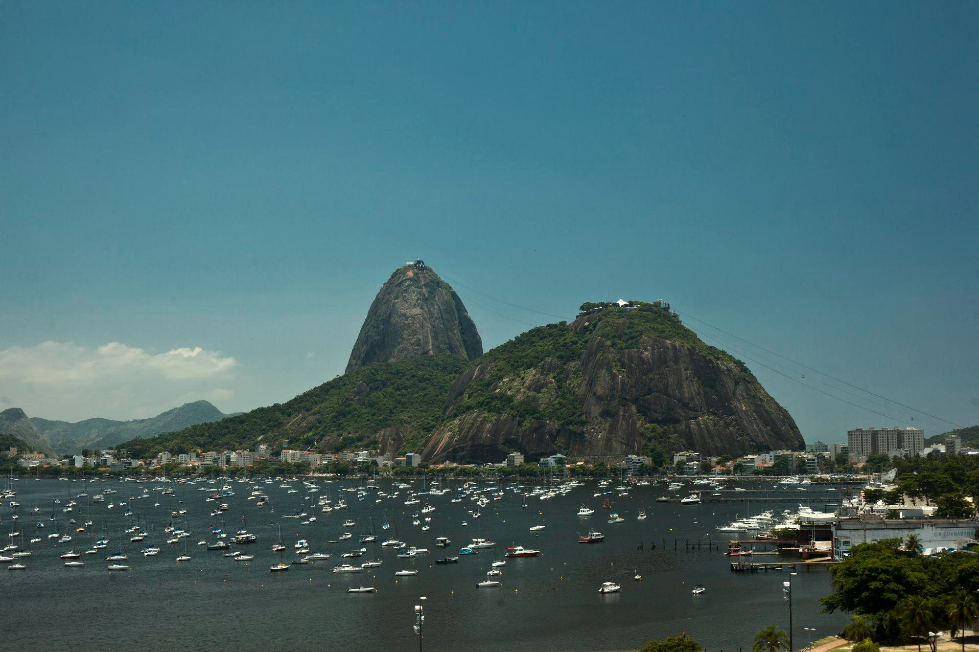Vista da Baía de Guanabara com o Pão de Açúcar e o Morro da Urca, e barcos ancorados.