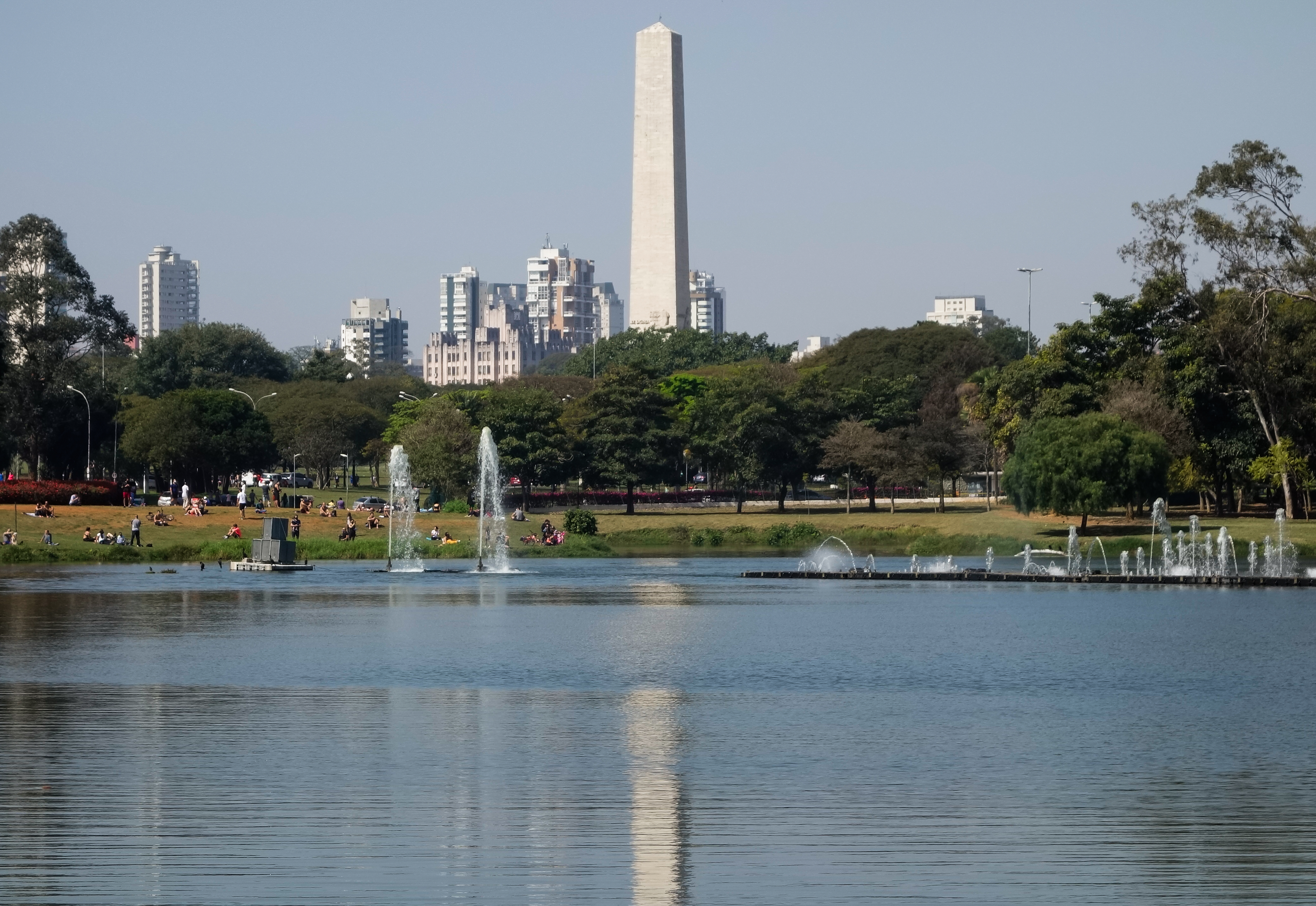 Lago com fontes no Parque Ibirapuera, com o Obelisco de São Paulo e edifícios ao fundo.