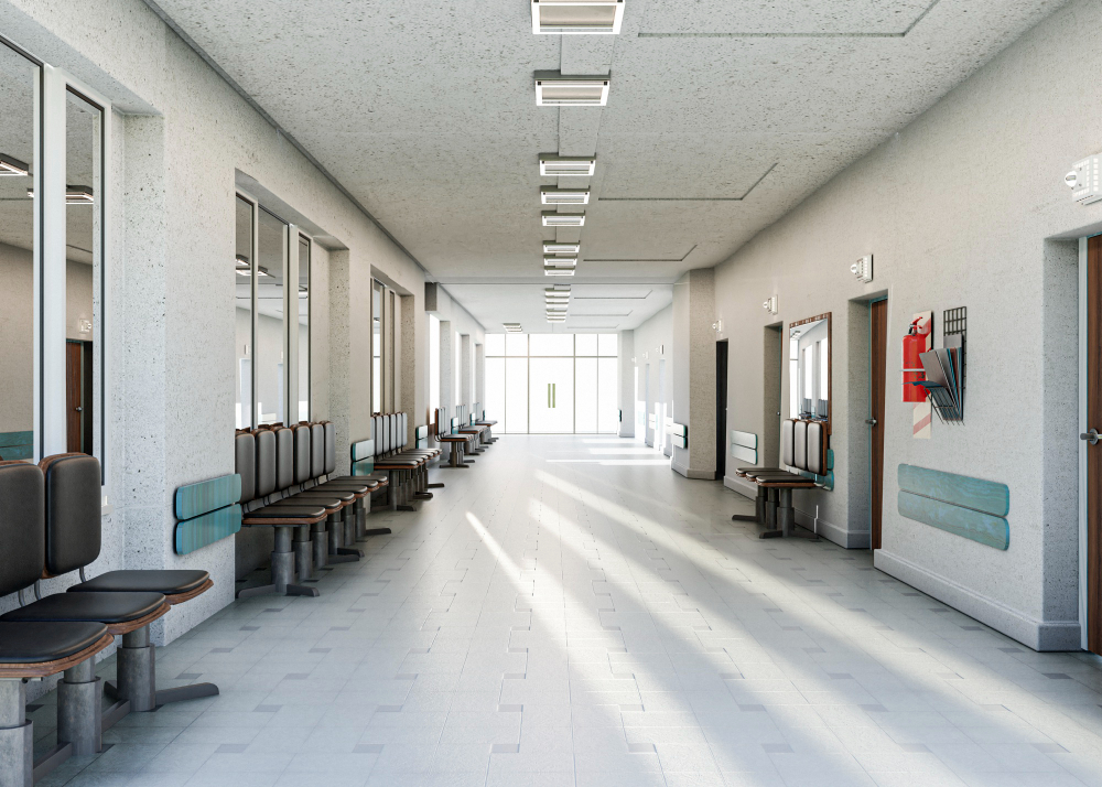 Um longo corredor de hospital ou clínica com cadeiras de espera em ambos os lados, portas nas paredes e luz brilhante vindo do final do corredor.