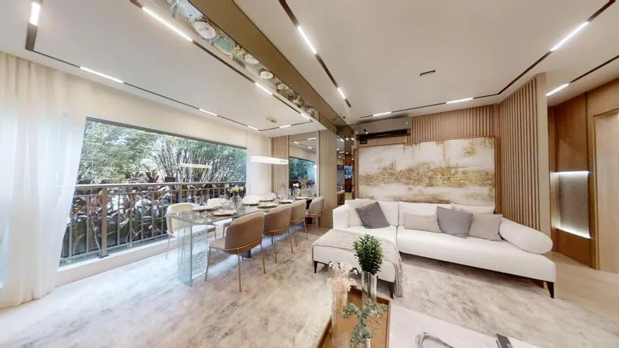 Sala de estar e jantar moderna e aberta com sofá secional branco, mesa de jantar de vidro com cadeiras bege, luzes de teto lineares e uma varanda com vista para uma área verde exuberante.